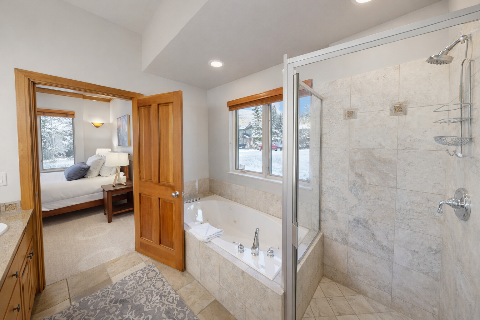 Unwind in your luxurious marble bathroom with soaking tub and glass shower, while winter views frame your perfect mountain retreat.