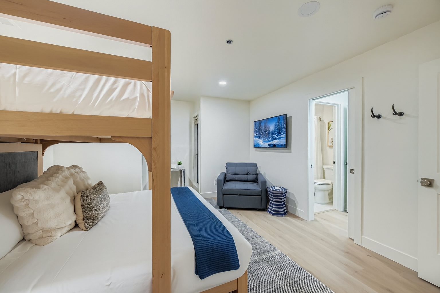 Relax in your modern room featuring a stylish bunk bed, cozy seating area, and private ensuite bathroom - perfect for a comfortable stay.