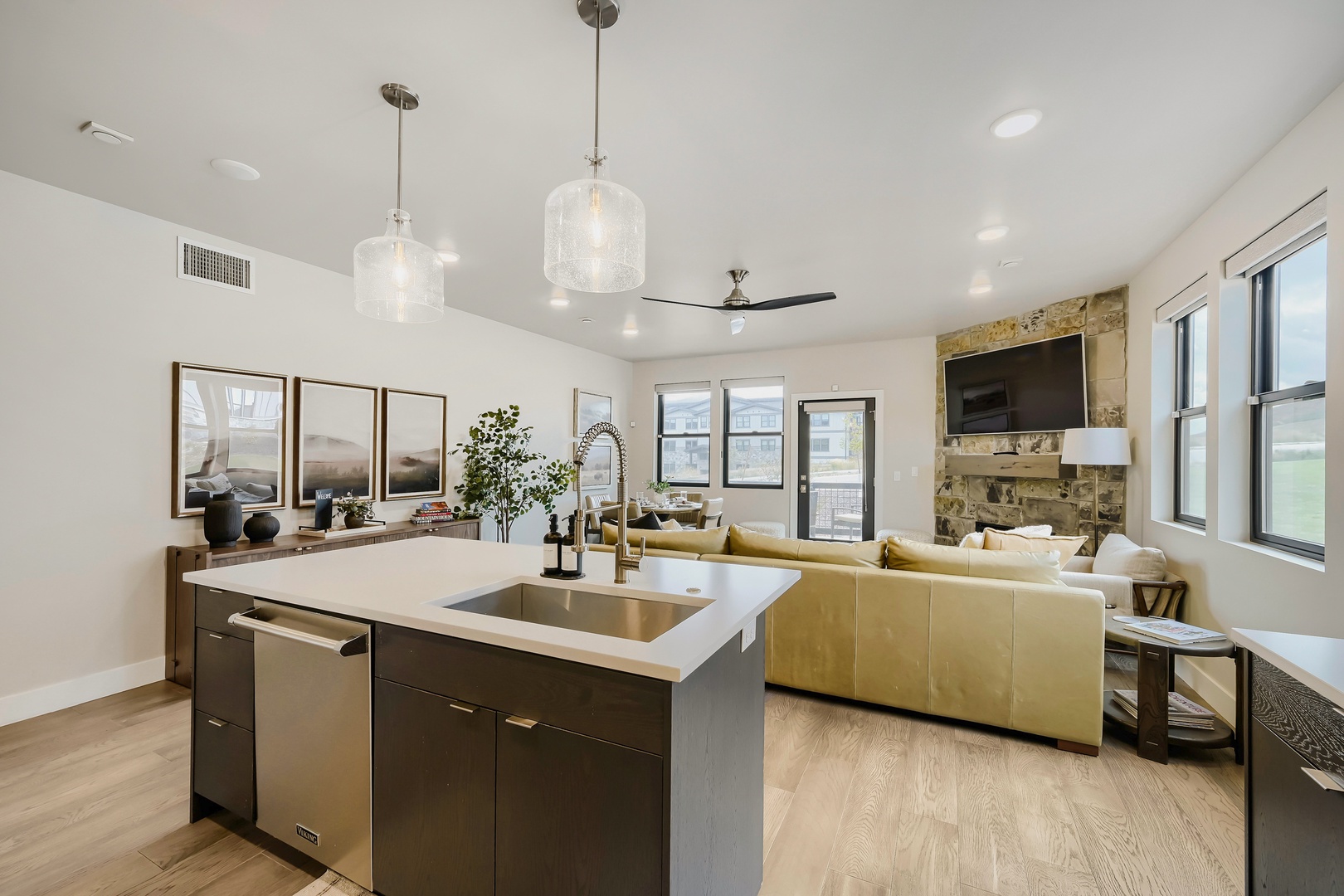 Gather in your open-concept living space where a sleek kitchen island flows into a sunlit lounge with golden accents and stone fireplace. Cook, relax, and unwind—all in one beautiful room.