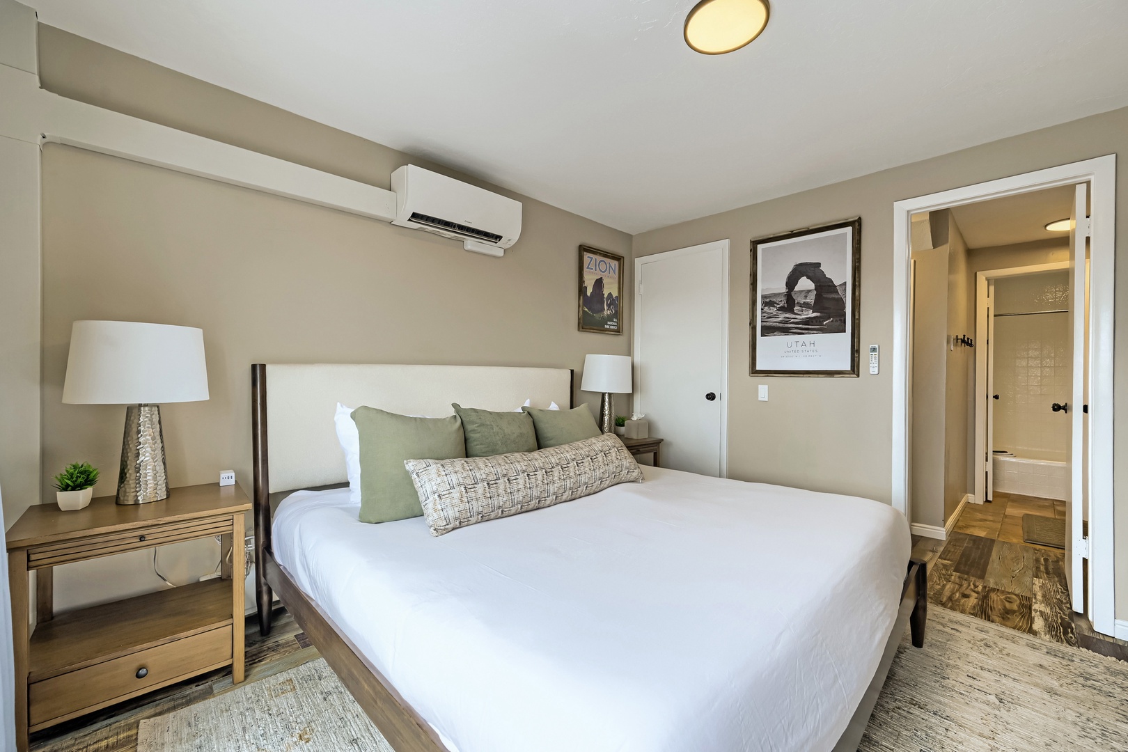 Your serene bedroom retreat features crisp white linens and calming sage accents, with climate control for perfect comfort. A private en-suite awaits just steps from your bed.