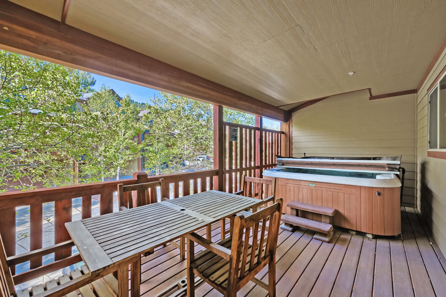 Relax on your private covered deck with a soothing hot tub and outdoor dining table surrounded by lush greenery and fresh mountain air.