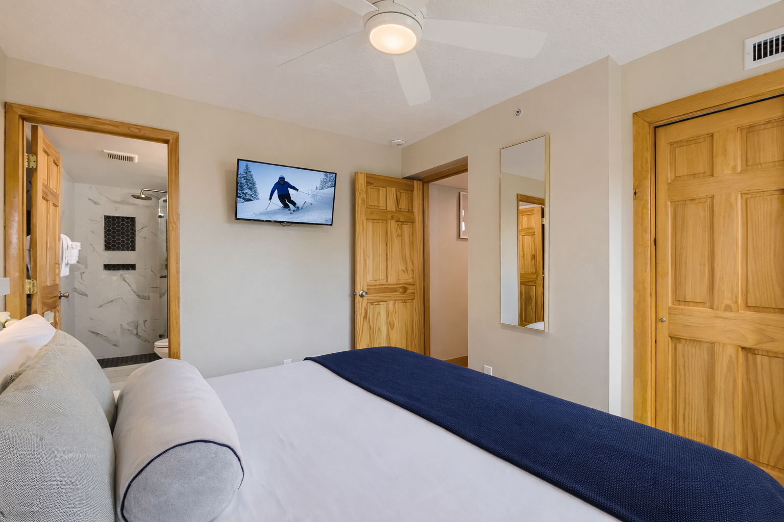 Peaceful primary bedroom with a comfortable king-size bed, ceiling fan, and lovely artwork.