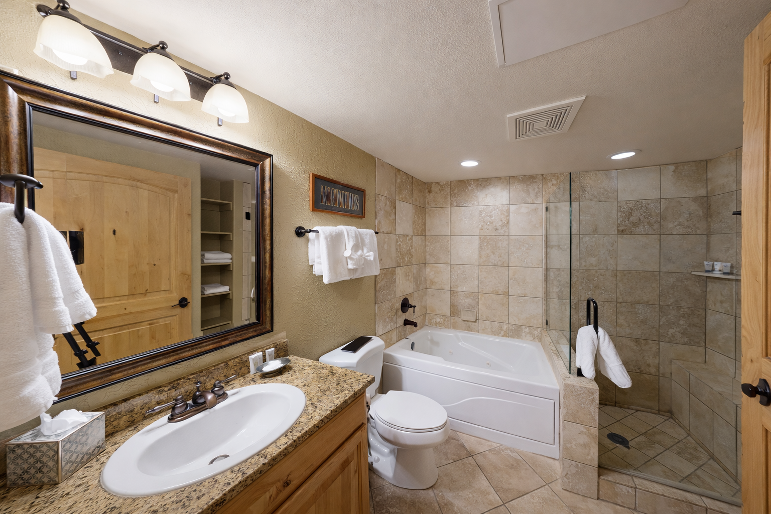 Indulge in this spa-like bathroom featuring a deep soaking tub, a sleek glass-enclosed shower, and elegant granite vanities. Refresh and recharge in style after your day of adventure.