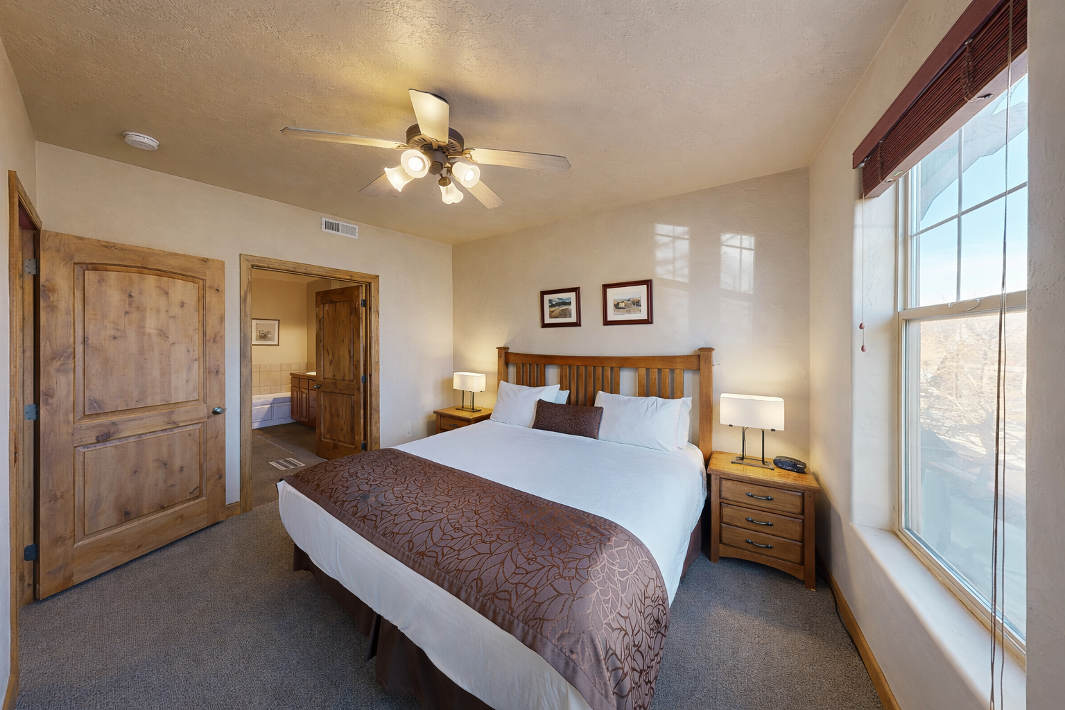 Unwind in your spacious bedroom with crisp linens, warm wood accents, and a ceiling fan to keep you comfortable year-round.