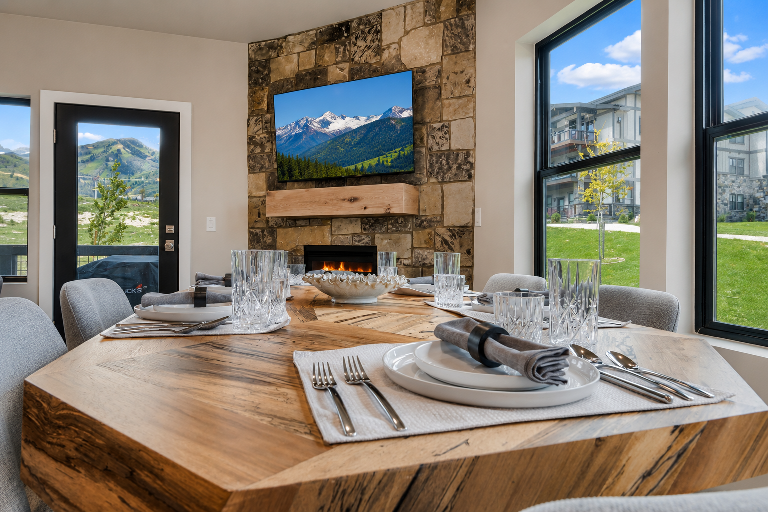 Gather around this stunning live-edge dining table with mountain views framing every meal. The cozy fireplace and natural stone accent wall create your perfect alpine retreat setting.