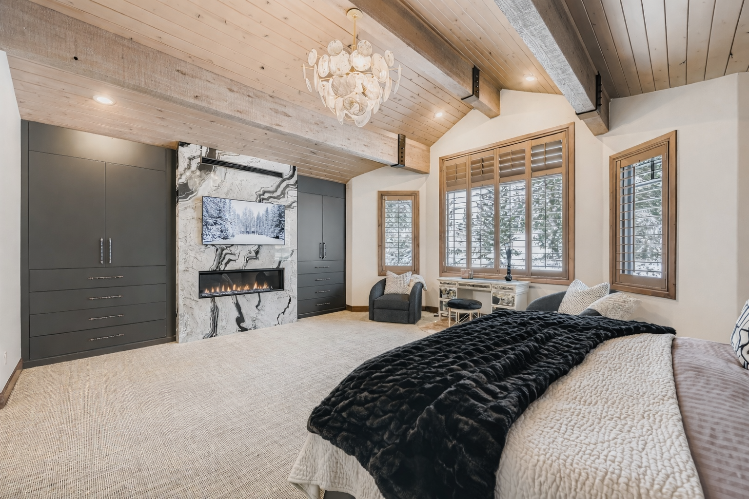 Unwind in your spacious master suite with vaulted wood ceilings, elegant chandelier, and cozy seating area - your perfect retreat after a day of adventure.