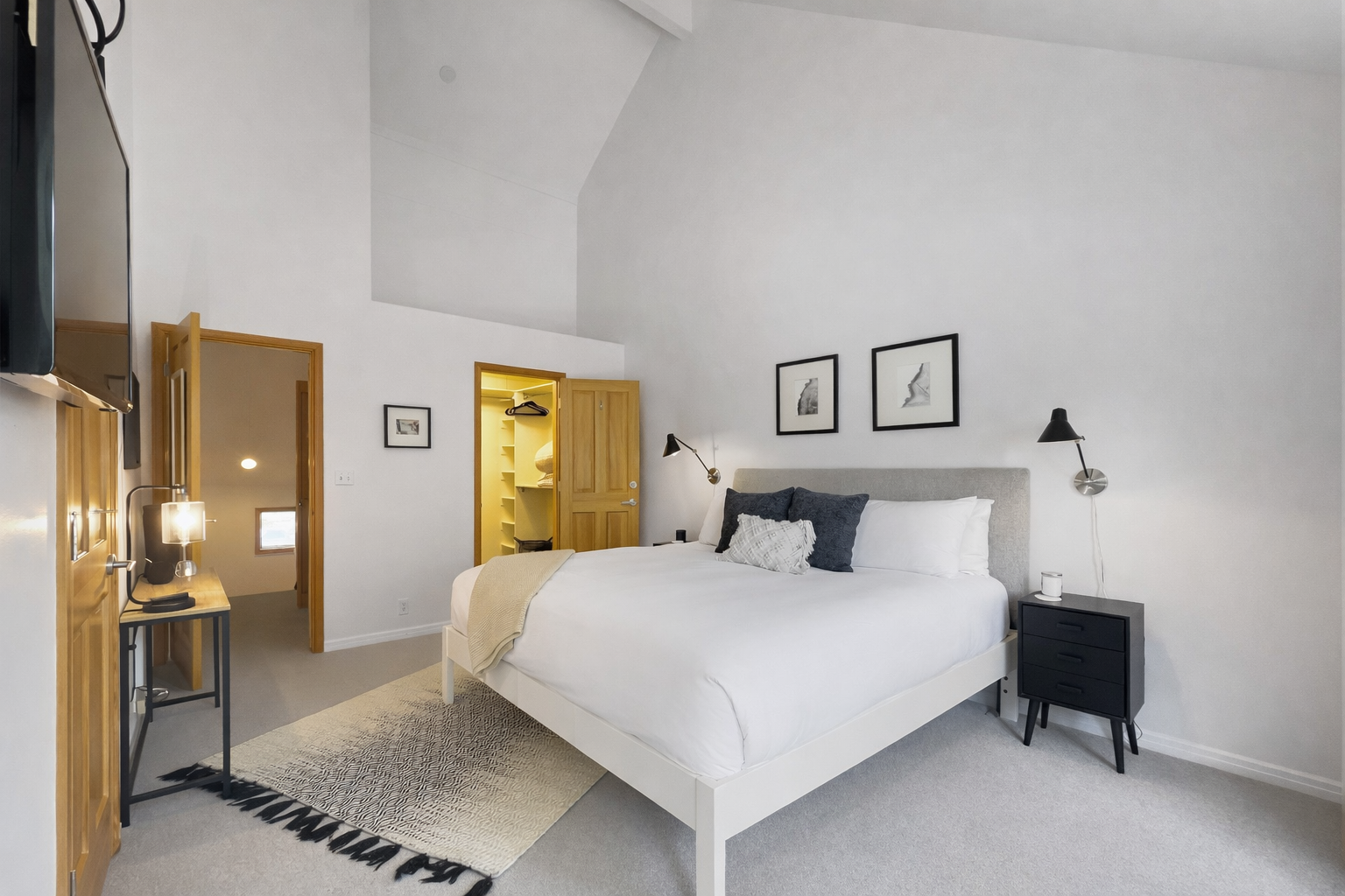 Retreat to this tranquil bedroom featuring a plush king-sized bed, a bright vaulted ceiling, and views of lush greenery for a serene escape.