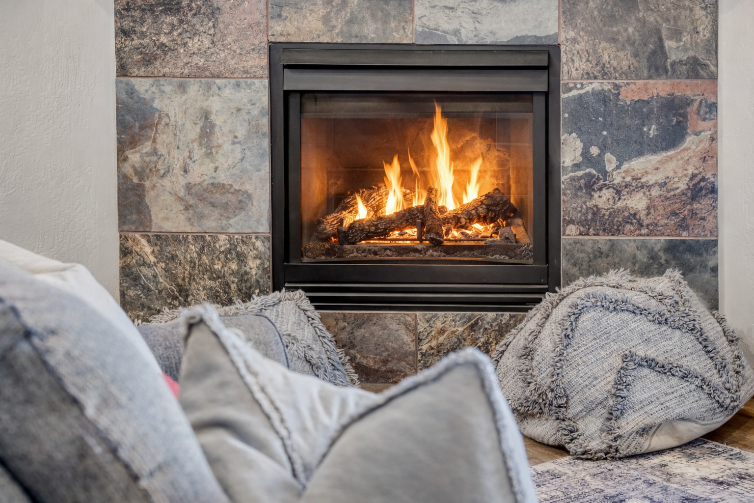 Curl up with soft throws by the crackling fireplace, where warm flames and cozy textures create your perfect retreat.