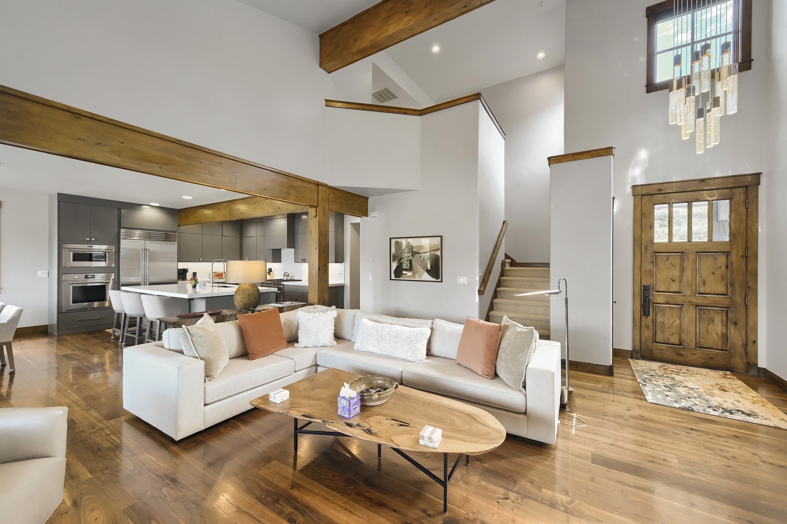 Step into this spacious open-concept retreat where rustic beams meet modern comfort. Plush seating, a natural wood coffee table, and a sleek kitchen flow seamlessly beneath soaring ceilings.