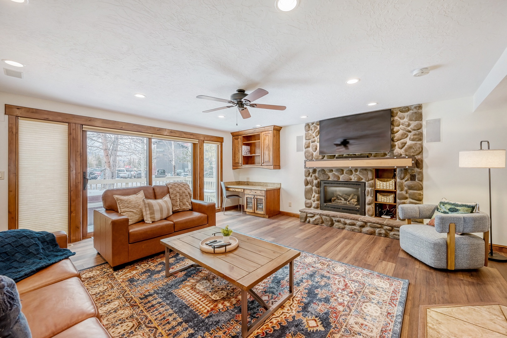 Cozy up in your spacious living room featuring a stunning stone fireplace, rich leather seating, and warm wood accents throughout.