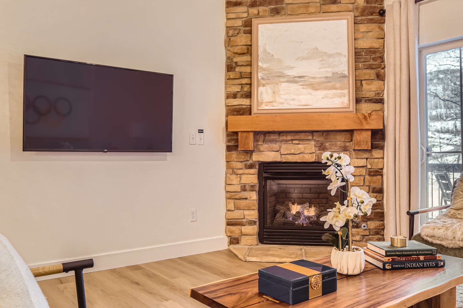Gather in this inviting living space where a warm stone fireplace and mountain views through large windows create your perfect après-ski retreat.