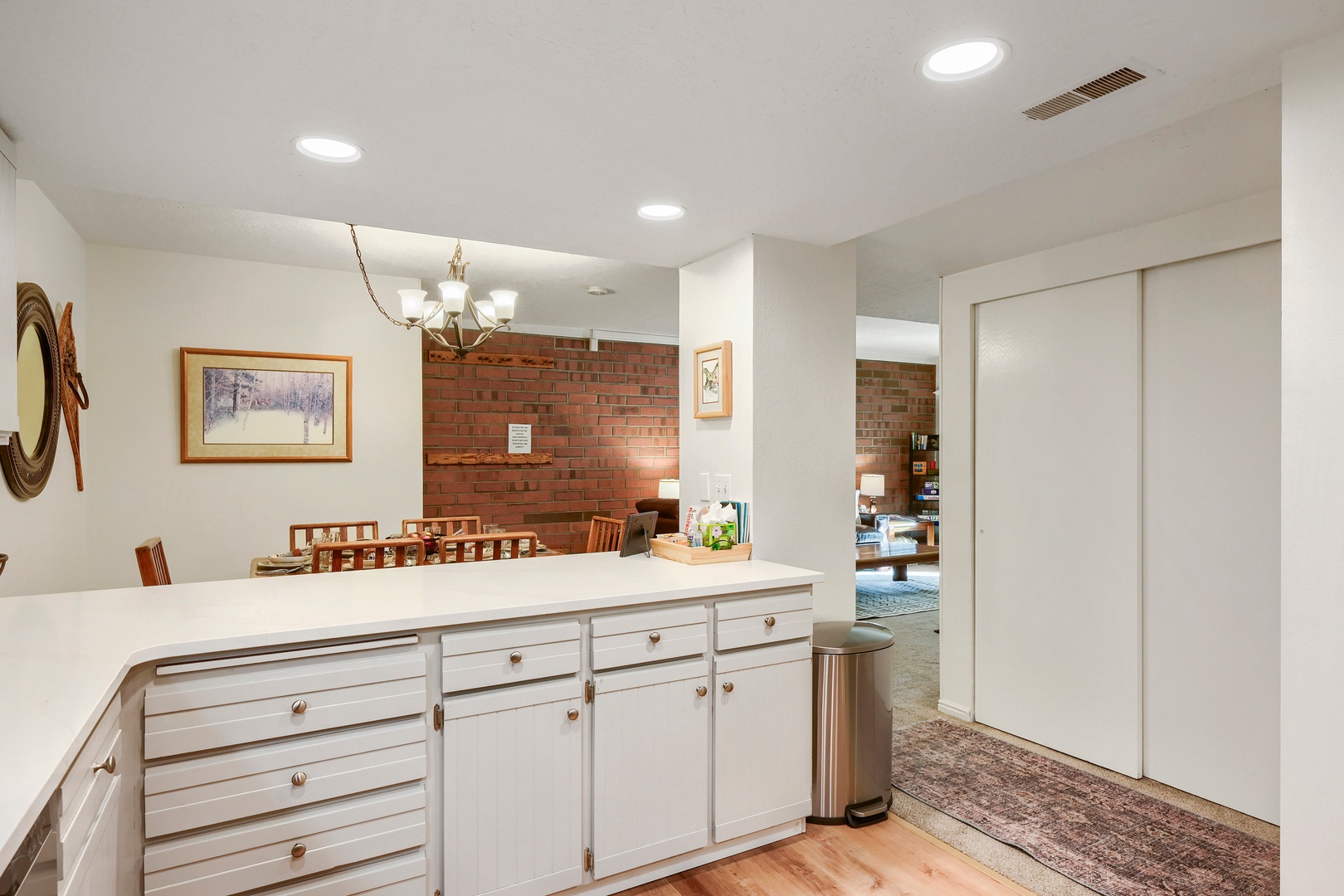 Step into this bright, open-concept space where rustic brick meets modern white cabinetry. Your dining area flows seamlessly into the kitchen, perfect for gathering with loved ones over meals and making memories together.