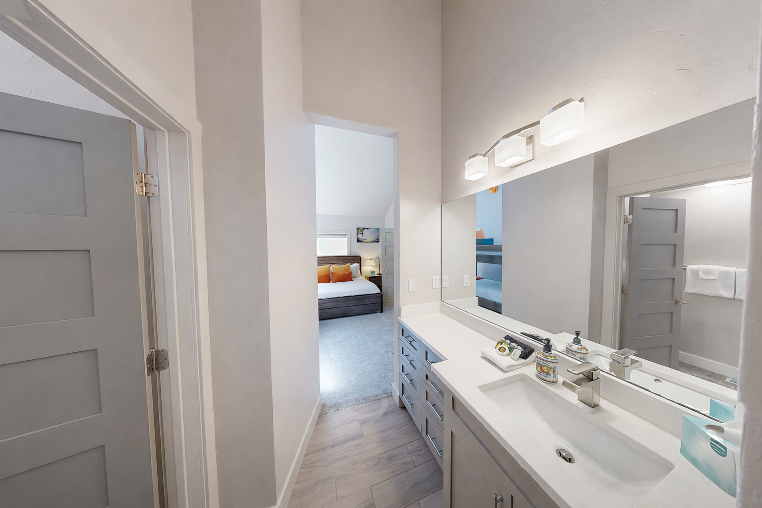Refresh in this bright, ensuite modern bathroom featuring a spacious white vanity and a large, well-lit mirror. A clean and functional space conveniently located near the guest bedrooms.