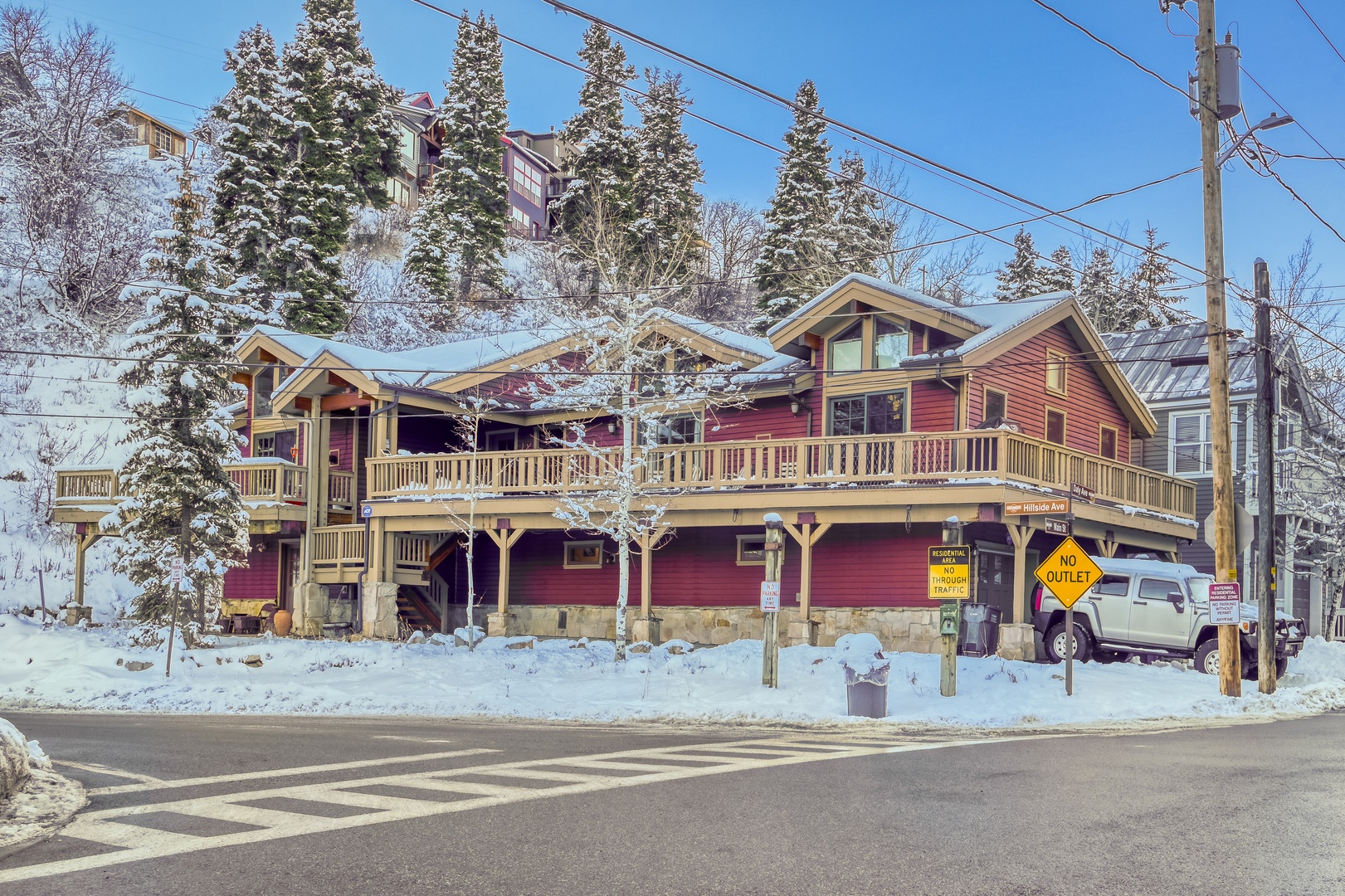Charming red mountain lodge nestled among snow-covered evergreens, offering cozy winter retreat accommodations in a picturesque alpine setting.