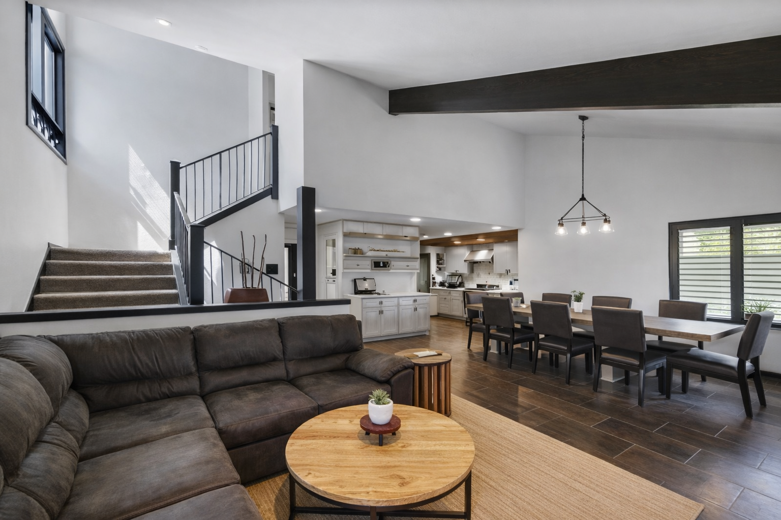 Open-concept living connects a modern kitchen, dining area, and cozy seating around a stone fireplace, perfect for gathering during your Park City getaway.