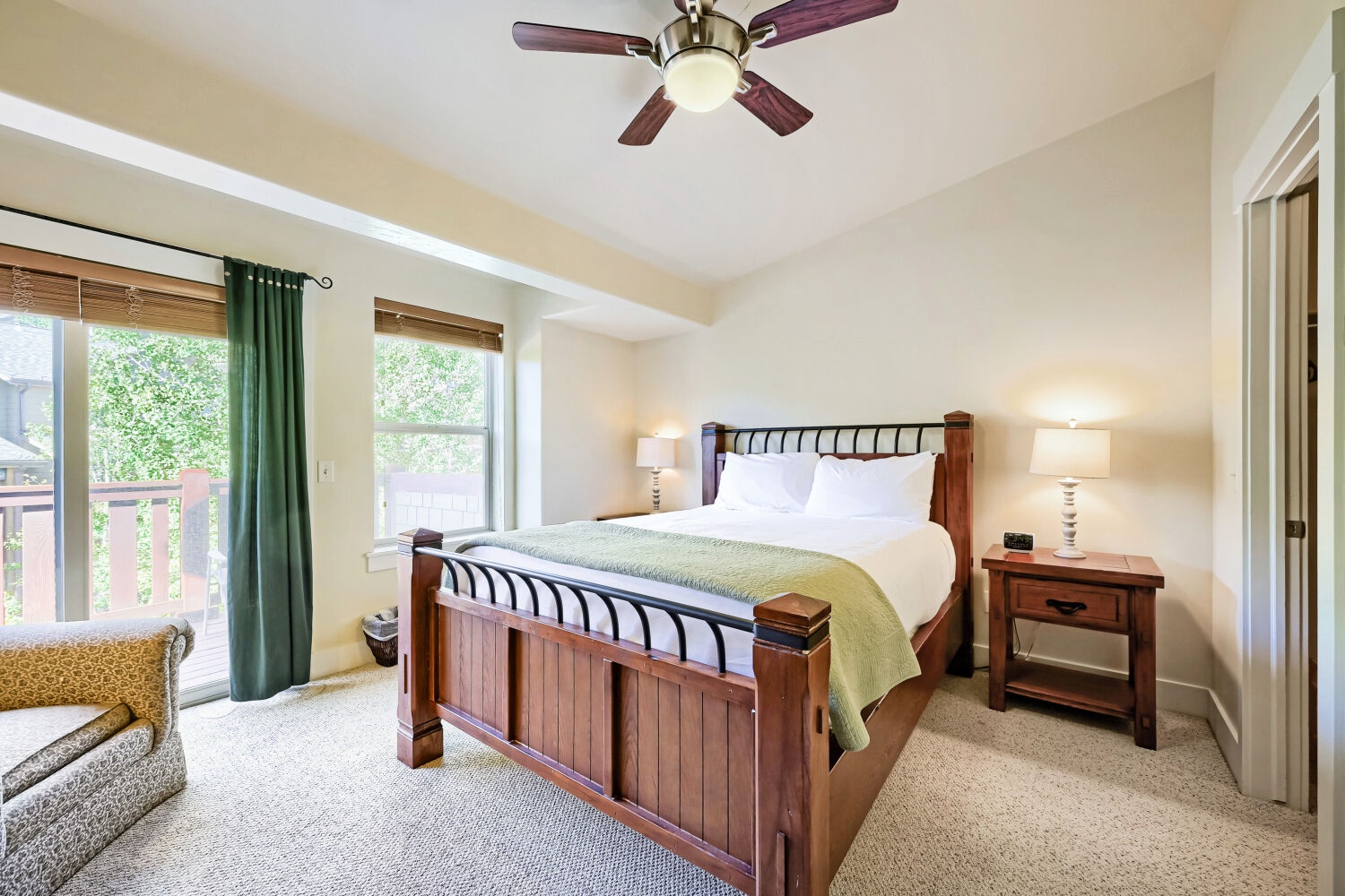 Your serene bedroom retreat features a plush bed, natural light from large windows, and a gentle ceiling fan to keep you cool. Relax in the cozy seating area and enjoy peaceful garden views.