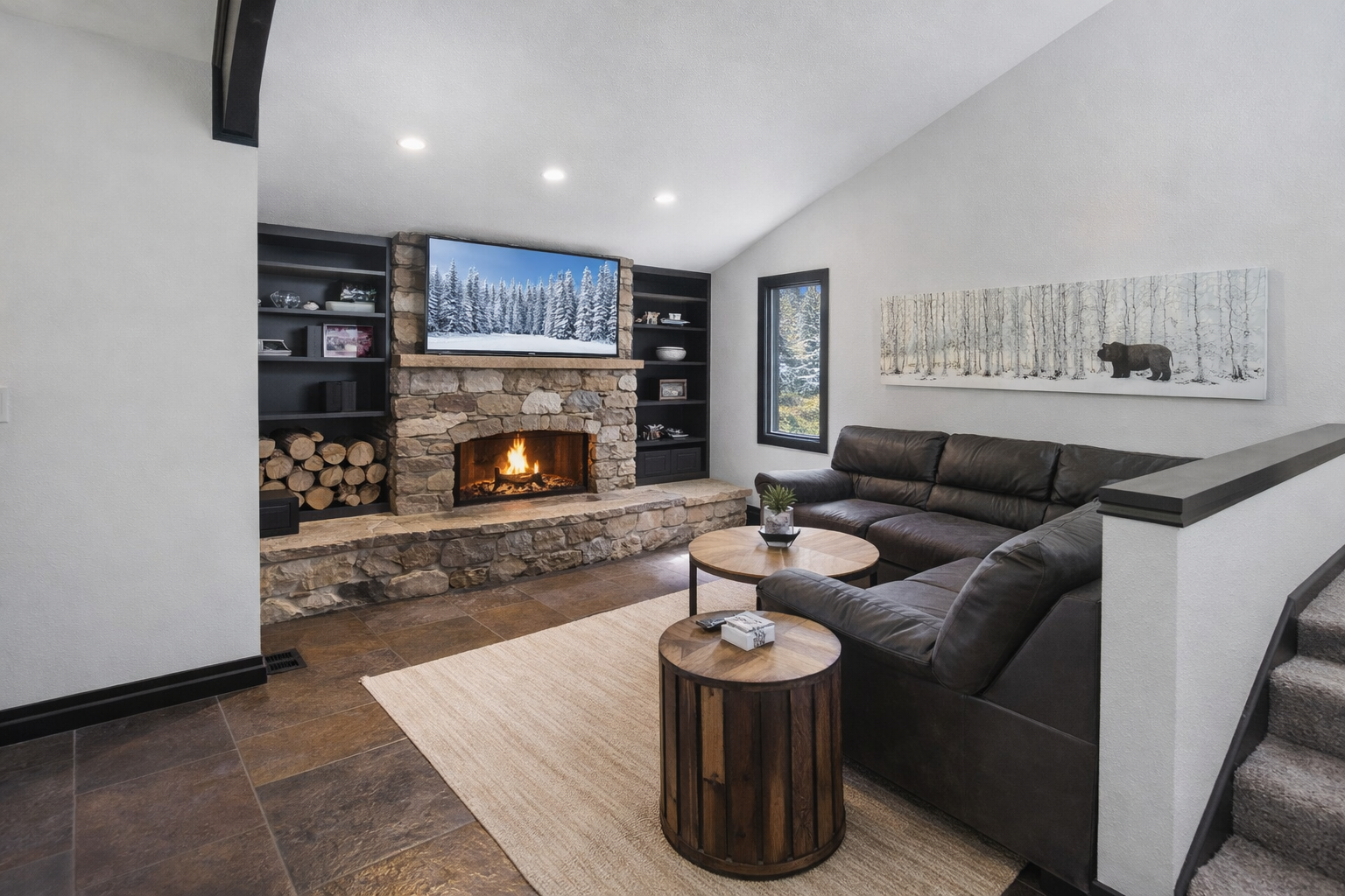 Cozy mountain living room with a modern stone fireplace, comfy sectional, and a serene rocking chair. Perfect for relaxing after a day of Park City adventures.