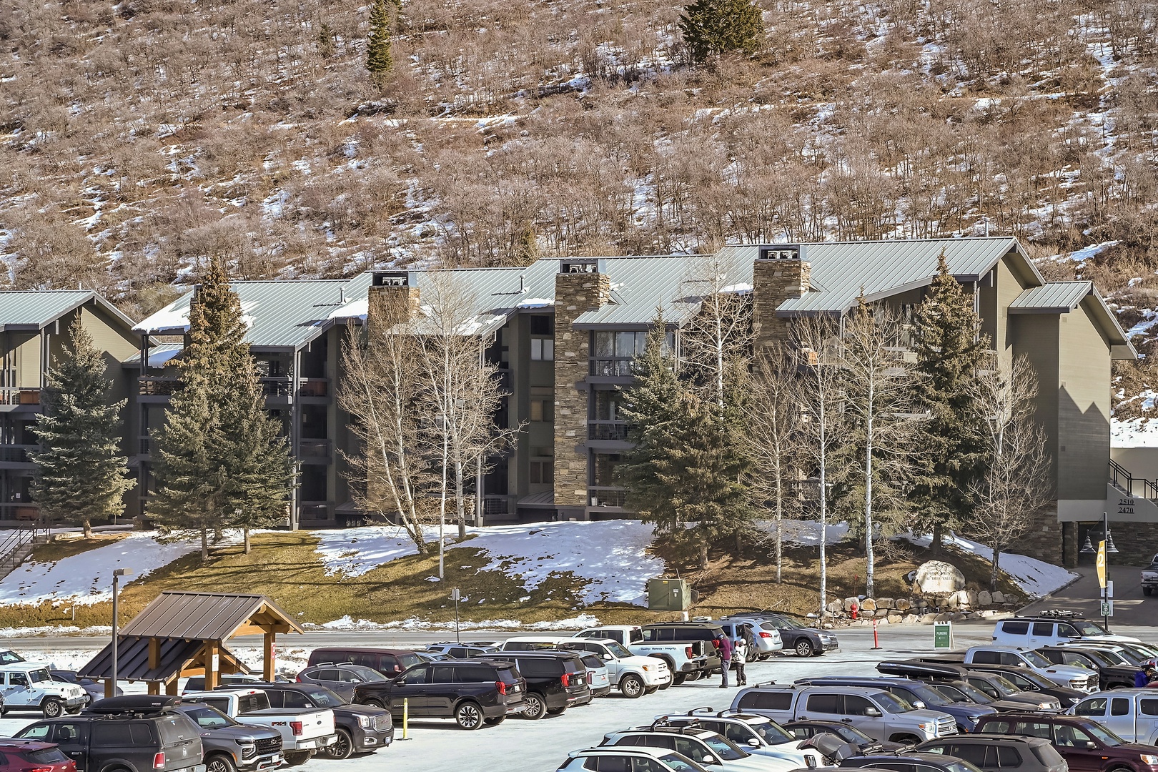 Mountain resort complex nestled against snowy hillsides with convenient parking and seasonal alpine charm.