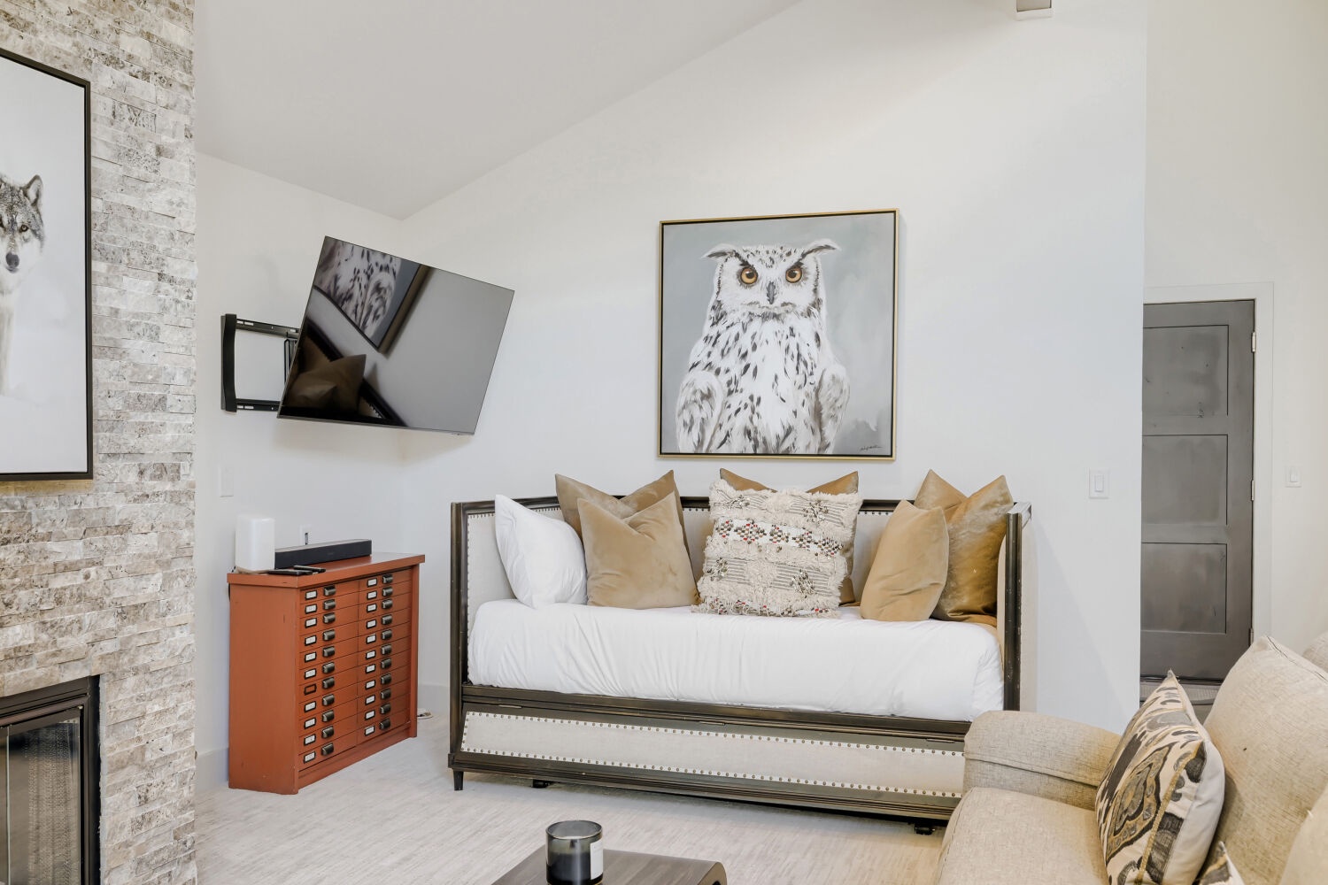 A bright living space with a cozy daybed, textured accent wall, and tasteful wildlife artwork creating a welcoming retreat for your stay.