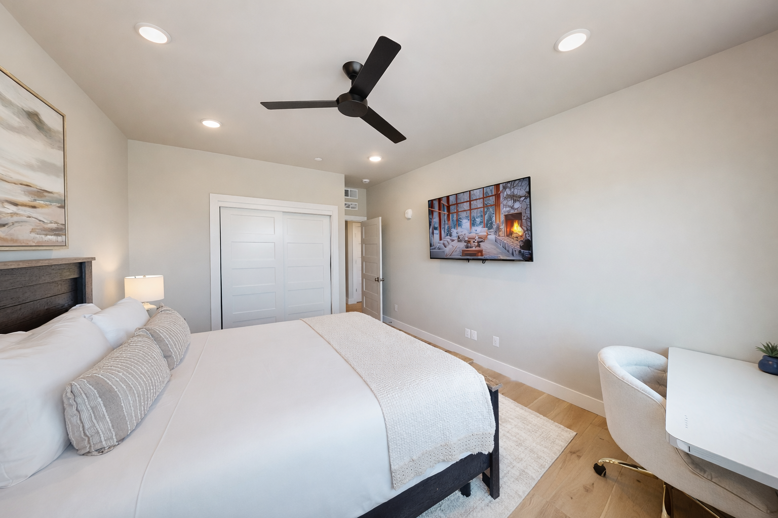 Unwind in your serene bedroom with crisp linens, modern touches, and a cozy fireplace scene on the wall-mounted TV.
