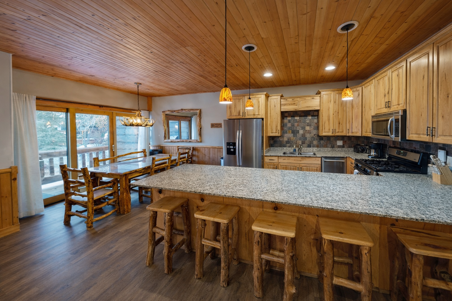 Gather around this spacious granite island with rustic log-style seating, where your group can cook, chat, and create memories together in a warm, mountain-inspired kitchen.