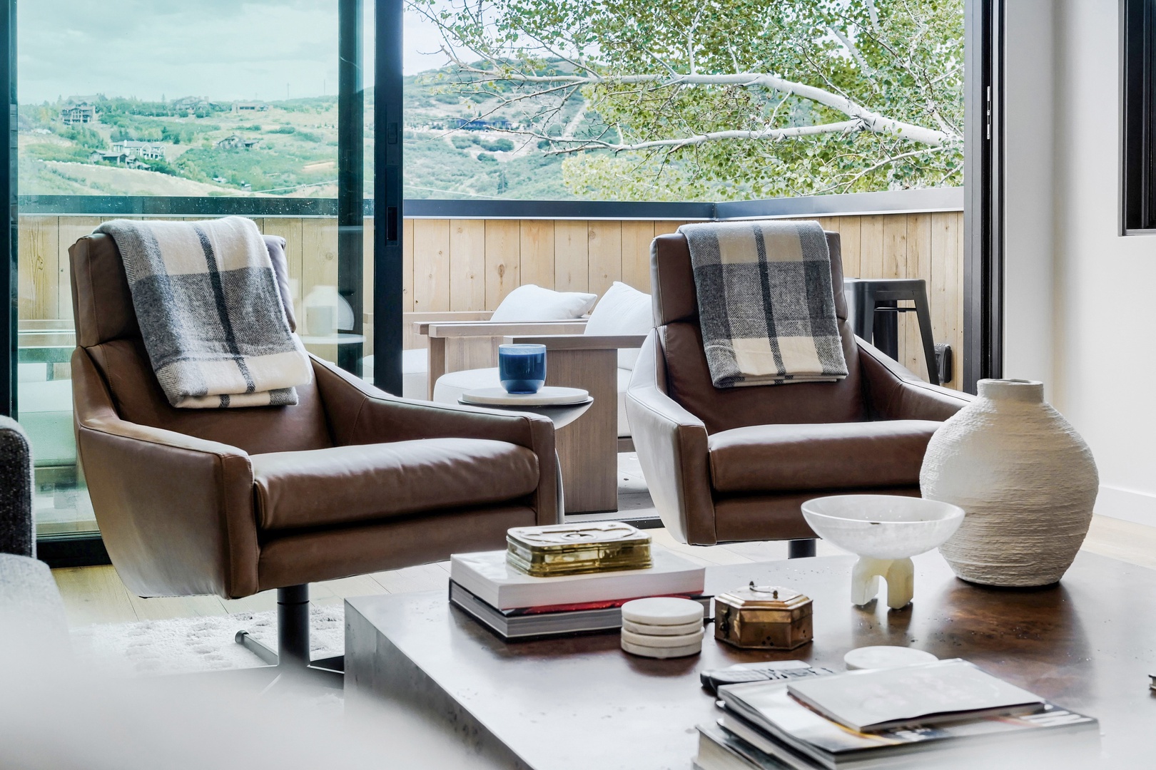 Sink into your private lounge space, where soft leather chairs and cozy throws invite you to unwind while taking in the sweeping hillside views through floor-to-ceiling windows.
