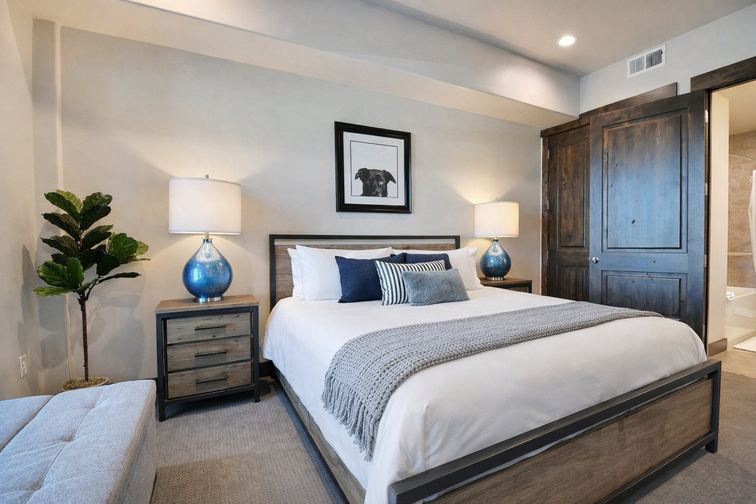 Sink into luxurious comfort with crisp white linens, stylish navy accents, and elegant blue ceramic lamps that create your perfect sanctuary.