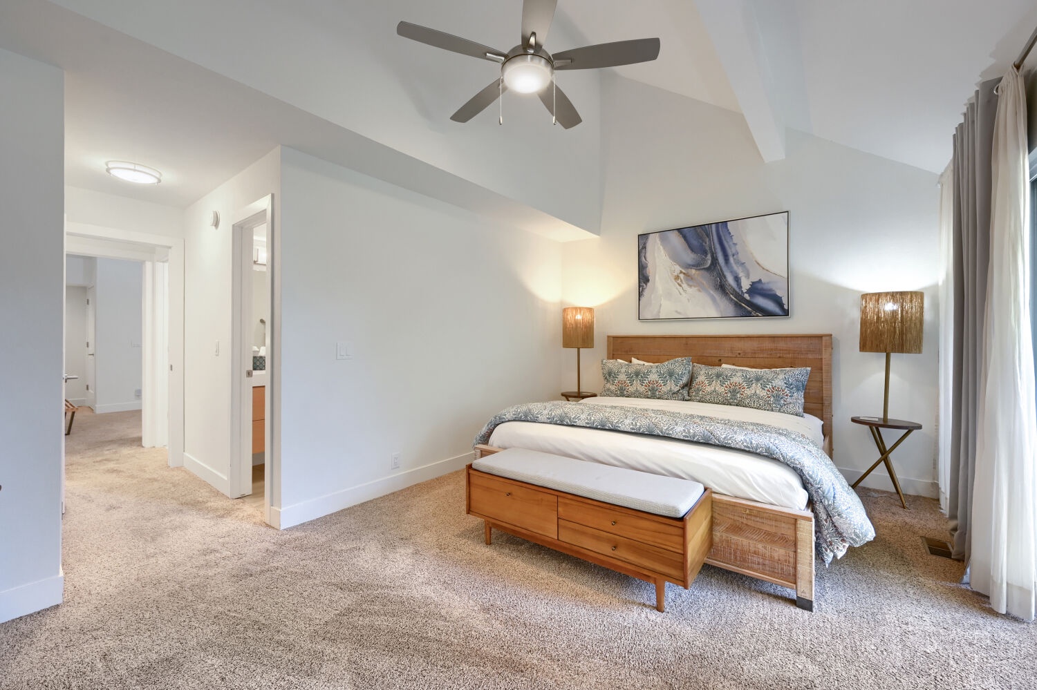 Step into your serene primary suite, where high ceilings and warm lighting create the perfect retreat after a day of adventure. Drift off in comfort beneath the ceiling fan.