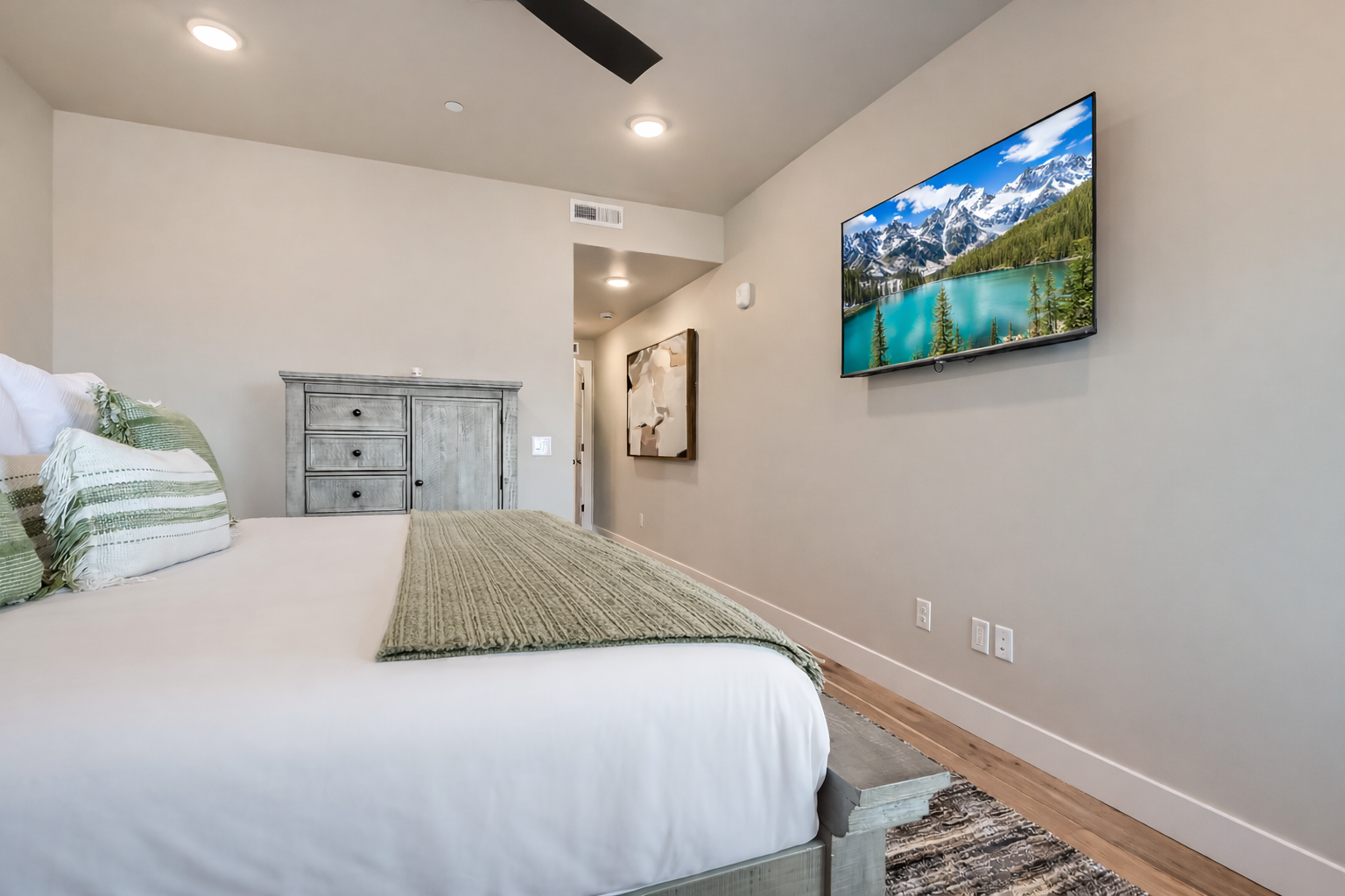Relax in this bright, modern bedroom featuring a plush king bed and sleek wooden accents. A serene mountain retreat with large windows—perfect for your next Park City adventure.