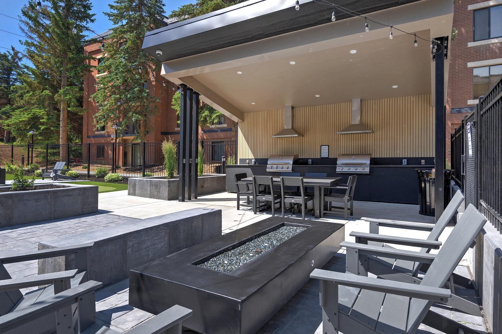 Modern outdoor pavilion features built-in grilling stations, comfortable lounge seating, and a sleek fire feature—perfect for gathering with friends or unwinding after exploring the area.