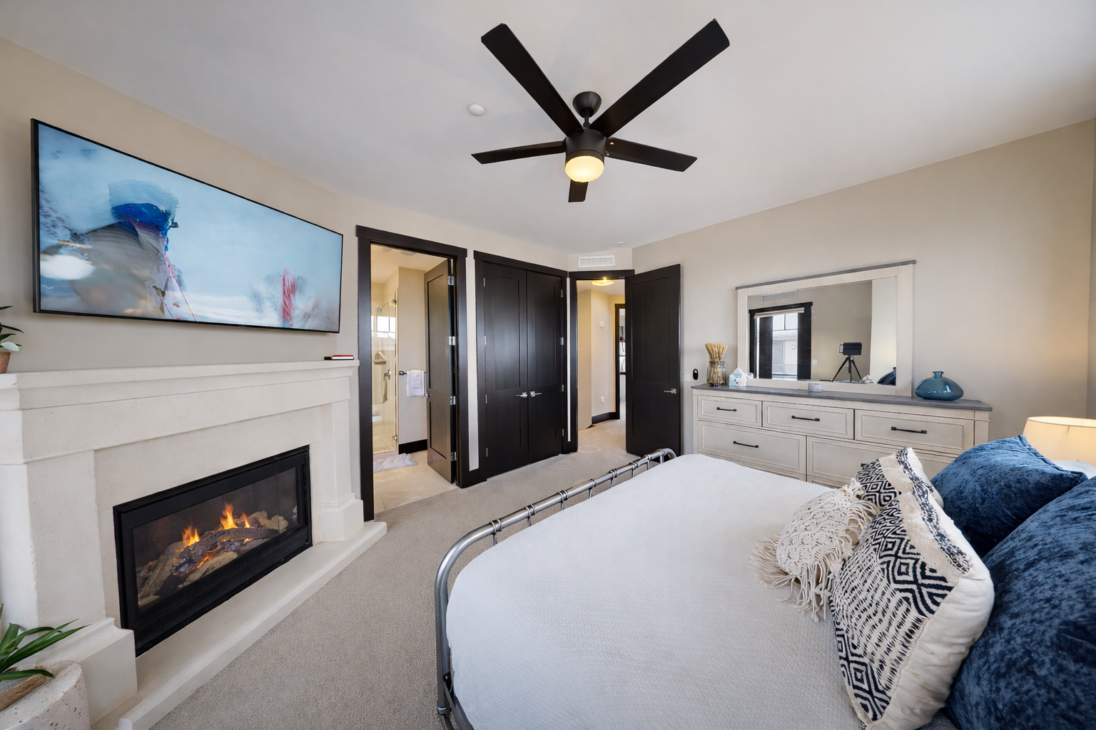 Relax in this bright master suite featuring a plush king bed and a cozy fireplace. Large windows and a private balcony offer serene views for a perfect mountain retreat.