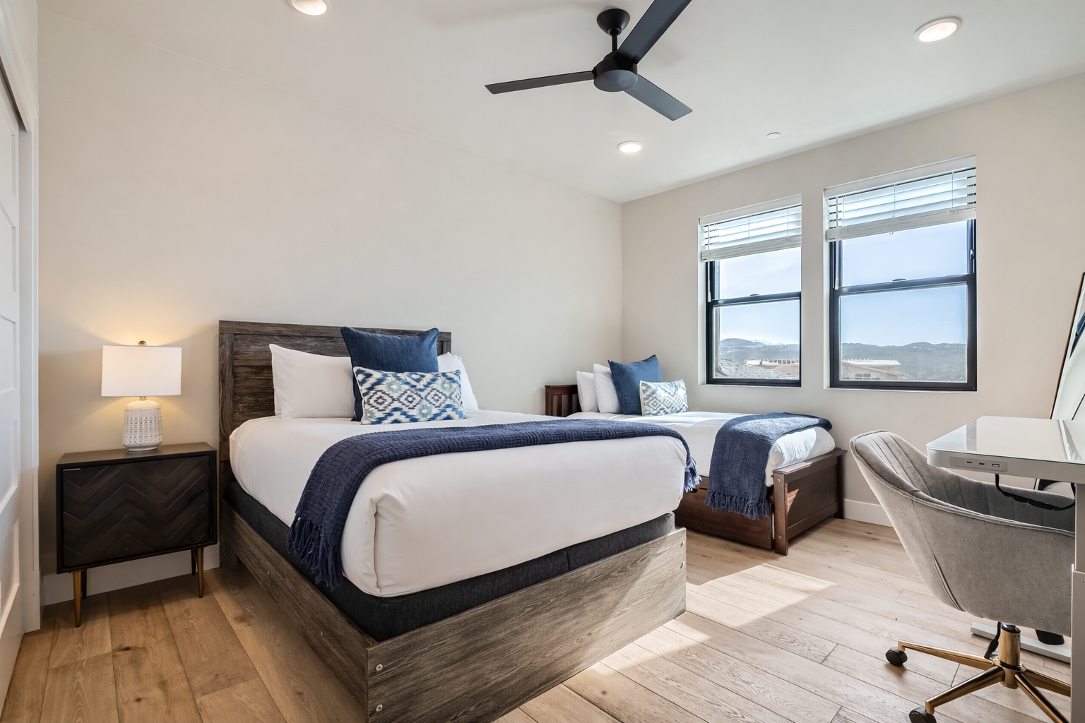 Relax in this bright, modern bedroom featuring two cozy beds with rustic wood frames. Sun-drenched and airy, it’s the perfect spot to rest and recharge after a day of exploring.