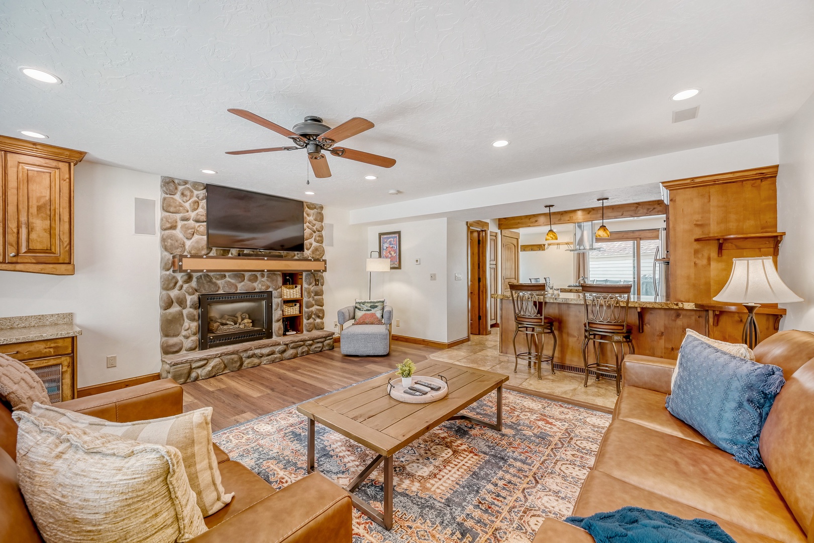 Cozy up by your stone fireplace in this warm living space, featuring rich leather seating and an open kitchen perfect for gathering.
