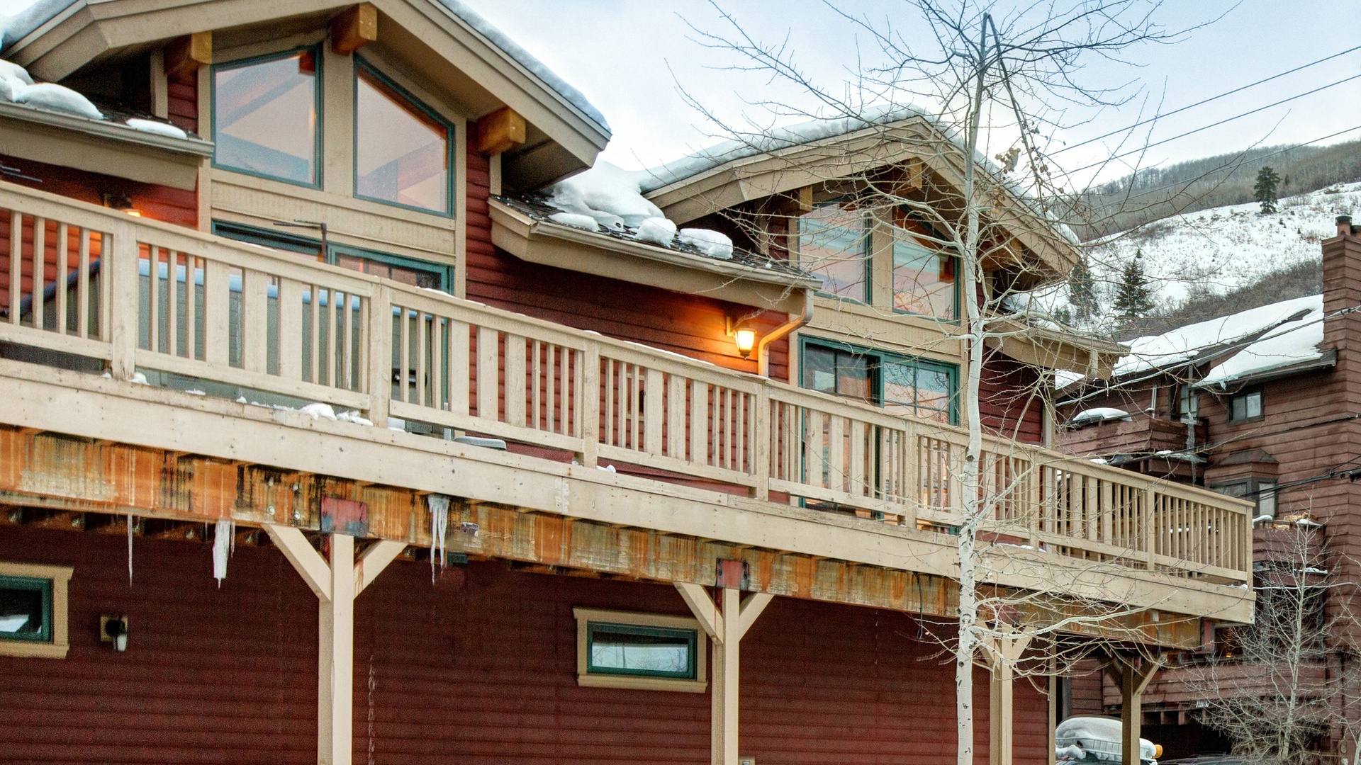 Rustic mountain lodge with snow-covered balcony and scenic alpine surroundings during winter season.