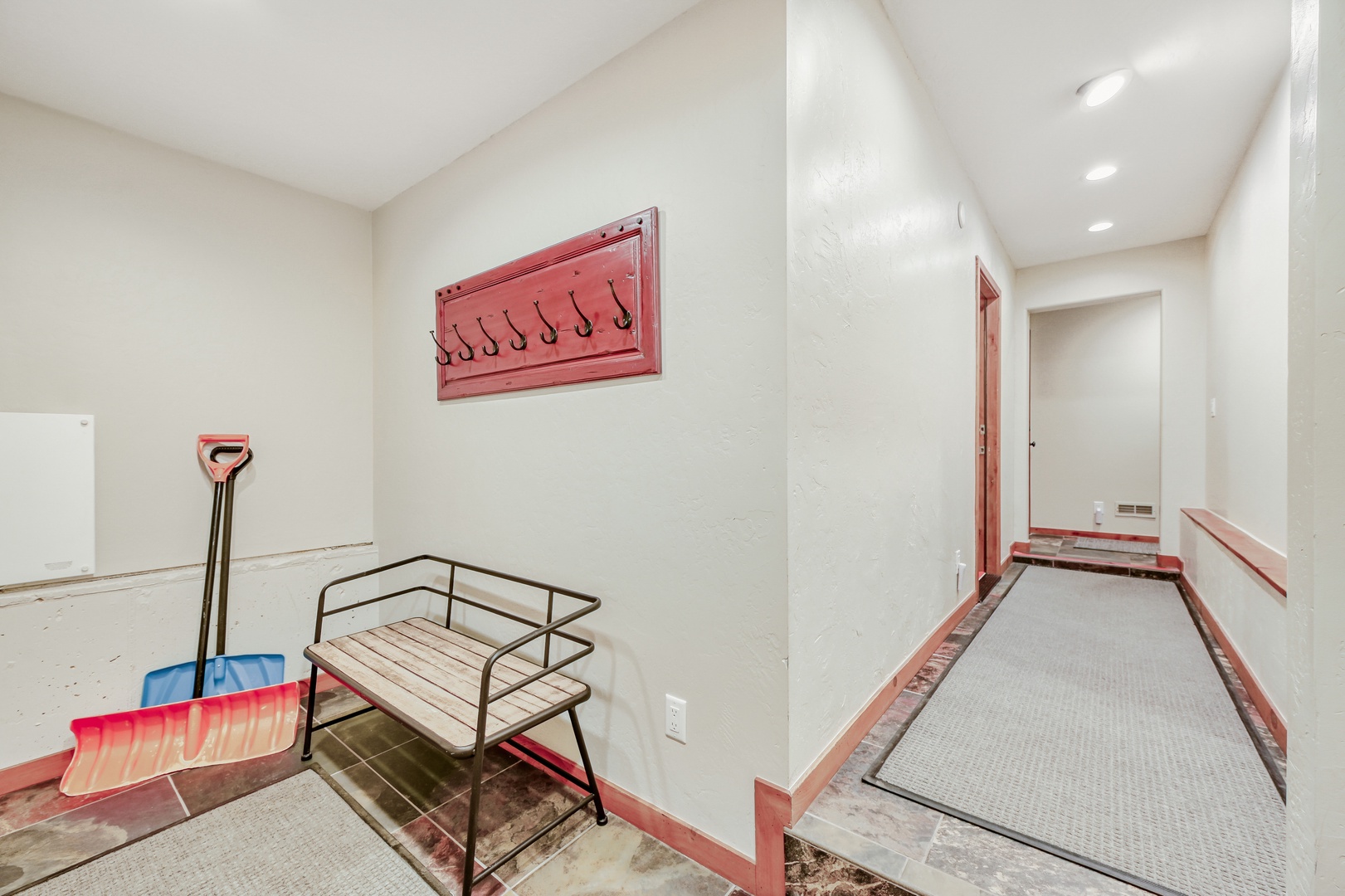 Your private ski storage area awaits, complete with bench seating and wall hooks for easy gear organization after mountain adventures.