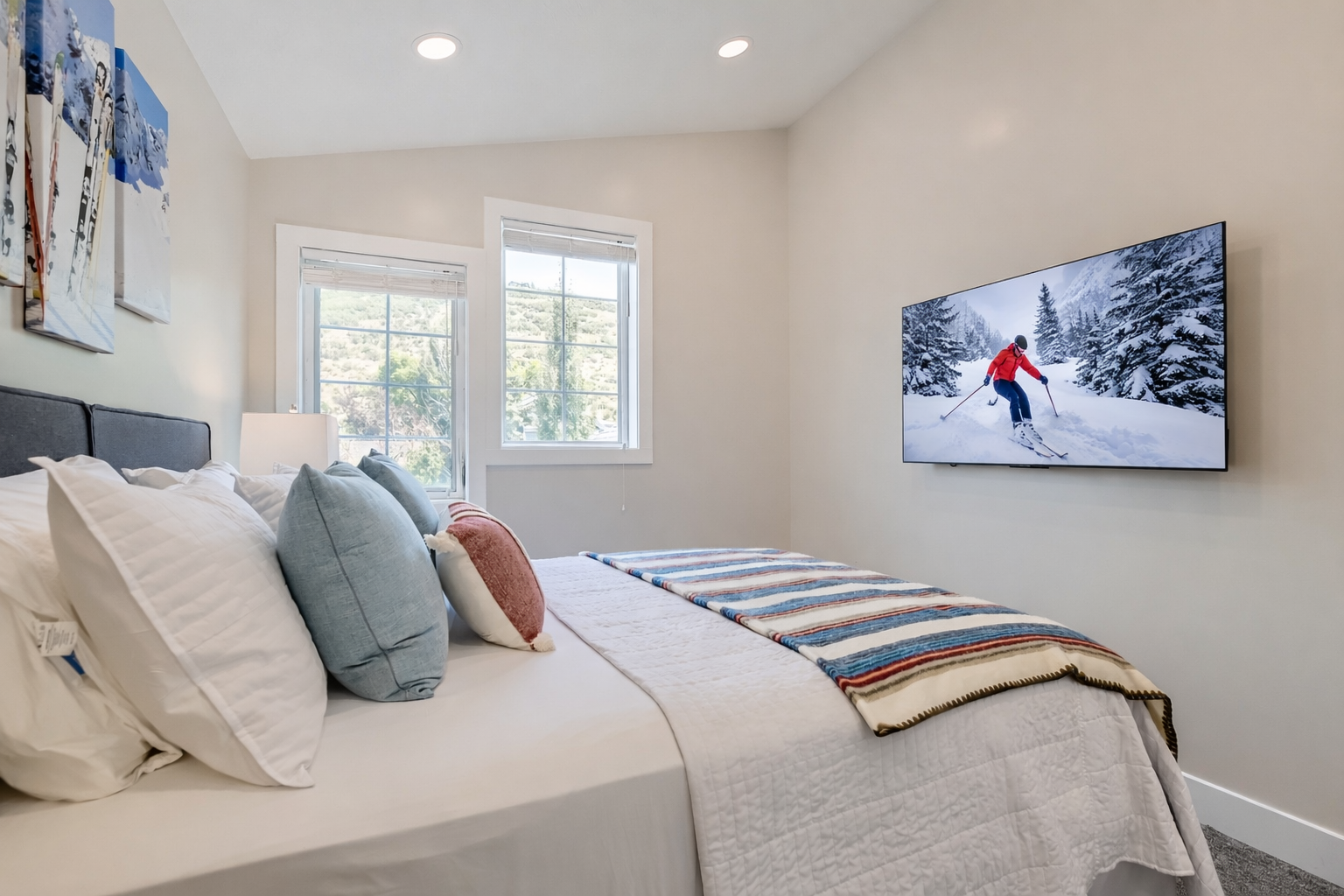 Drift off in this cozy bedroom featuring soft linens, mountain views through bright windows, and a large TV for your entertainment.