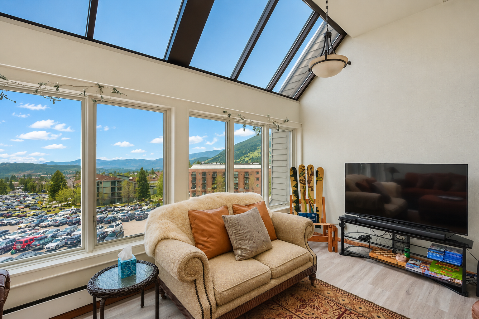 Unwind on your plush sofa under a stunning skylight while soaking in expansive mountain views through floor-to-ceiling windows—your bright, airy retreat awaits.
