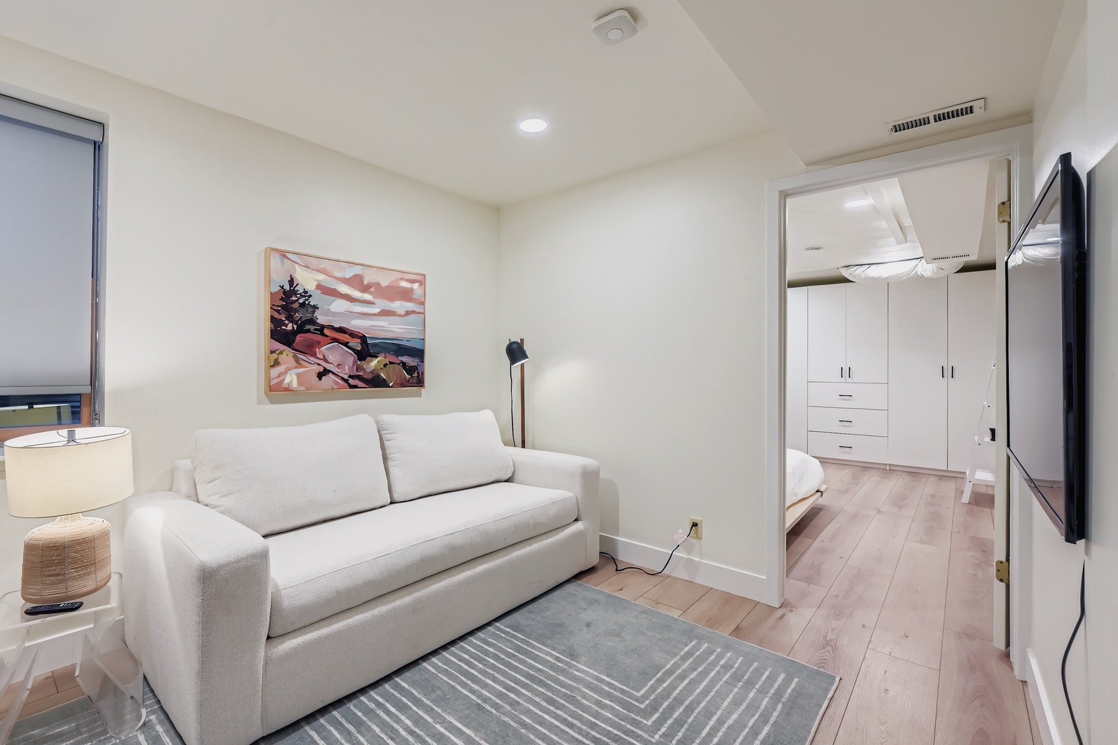 Sink into your private retreat with a plush sofa perfect for morning coffee or evening relaxation. The warm wood floors and calming artwork create a peaceful atmosphere where you can truly unwind.