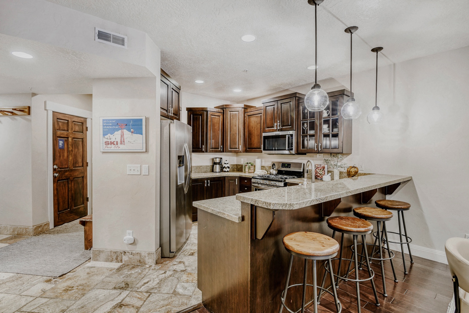 Your fully equipped kitchen features rich wood cabinetry, granite countertops, stainless steel appliances, and a breakfast bar with seating—perfect for preparing meals and gathering with friends.
