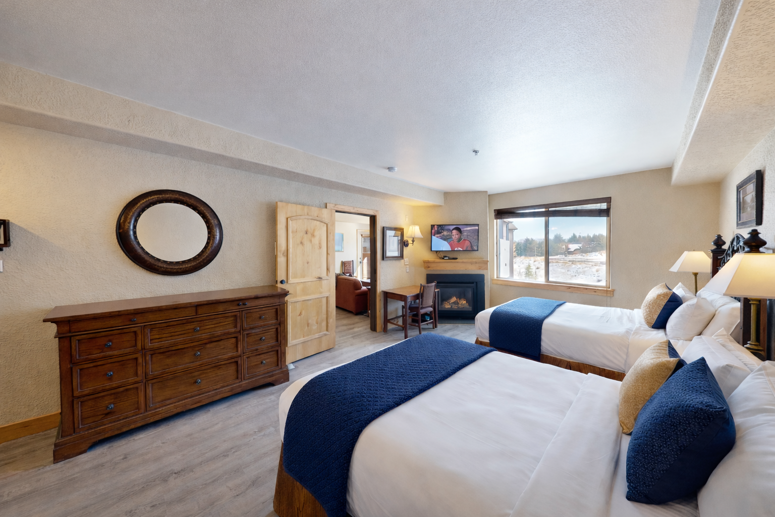 This spacious guest room features two plush queen beds with ornate wrought-iron headboards. Enjoy the convenience of a private kitchenette and sleek wood flooring, perfect for a group getaway.