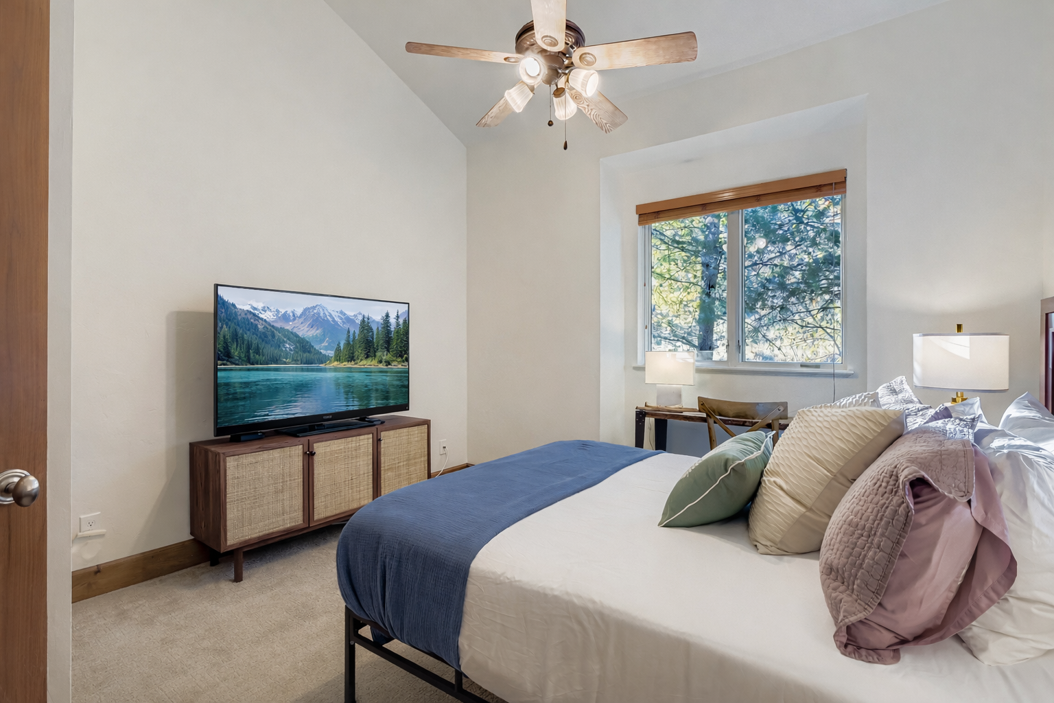 Settle into the cozy third bedroom, featuring a comfortable bed on a simple metal frame, bright windows, and a ceiling fan for climate control, ensuring a restful night's sleep.