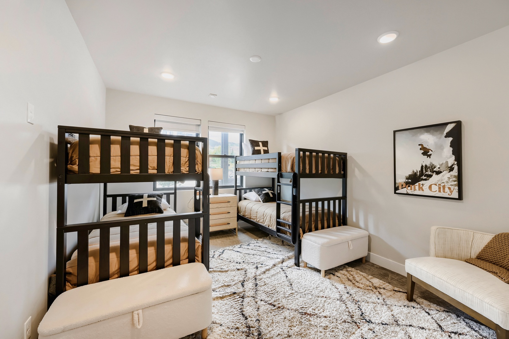 Bright, cozy bunk room with two sturdy bunk beds, plush ottomans, and soft rug. Ideal for families or groups seeking comfort and togetherness.