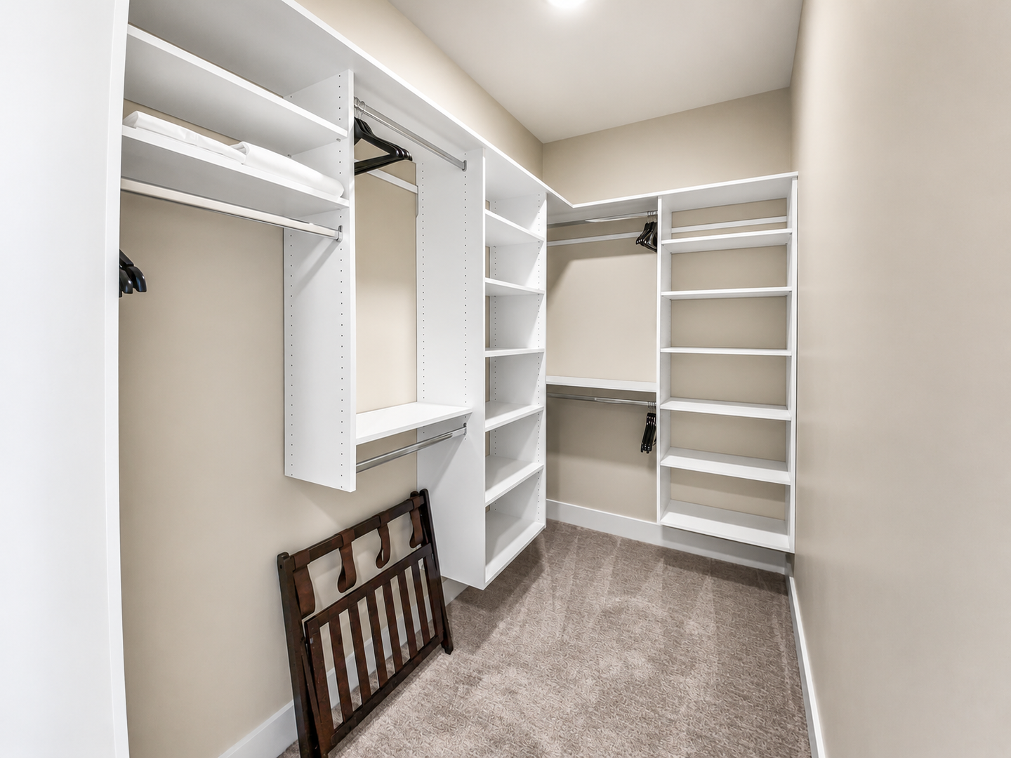 This spacious walk-in closet features custom white shelving with adjustable racks and hanging rods, providing ample storage for your wardrobe and belongings throughout your stay.
