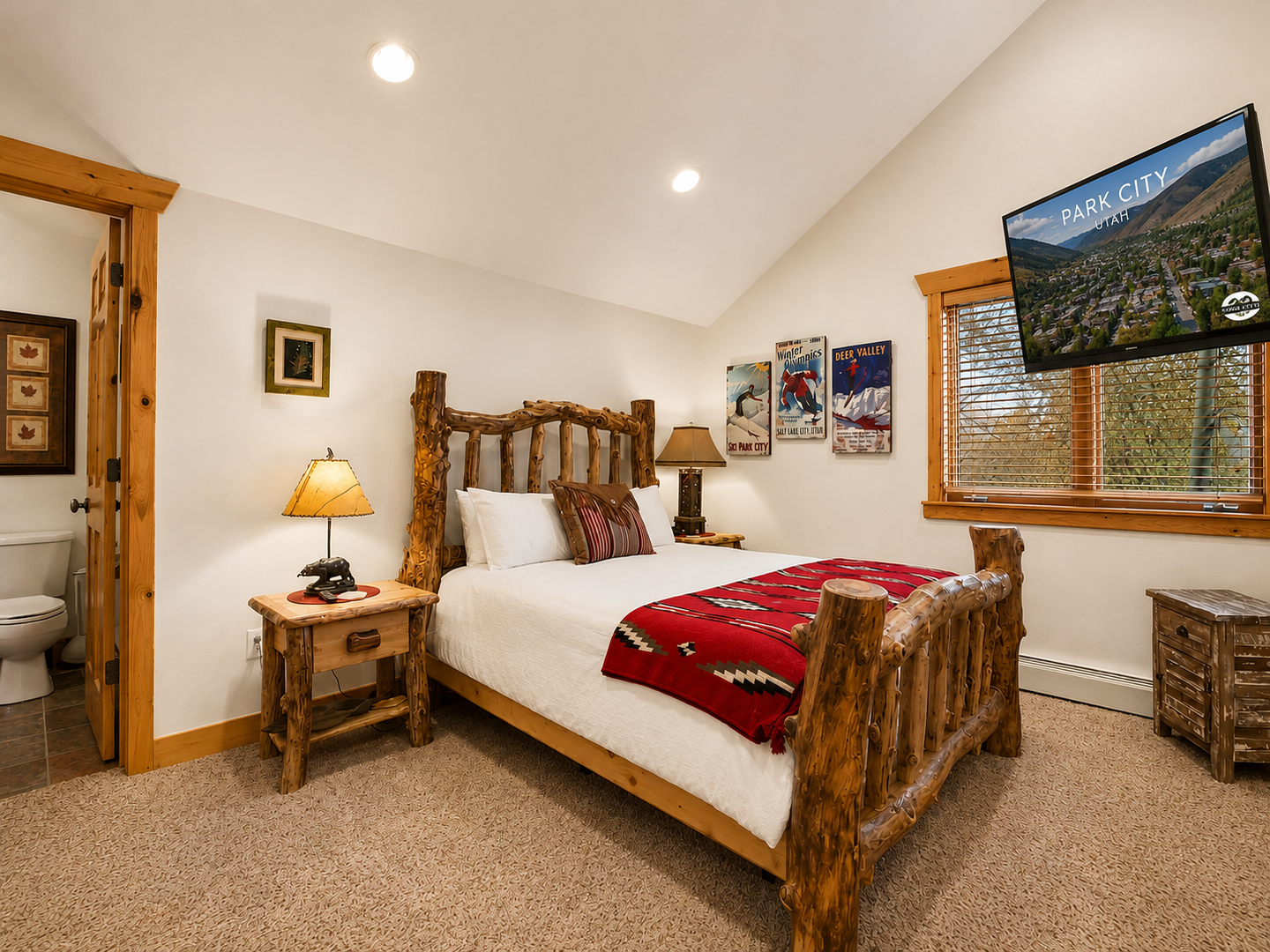 Sink into this inviting bedroom where rustic log furniture meets modern comfort, with crisp linens, warm lighting, and vintage ski posters setting a cozy mountain retreat vibe.