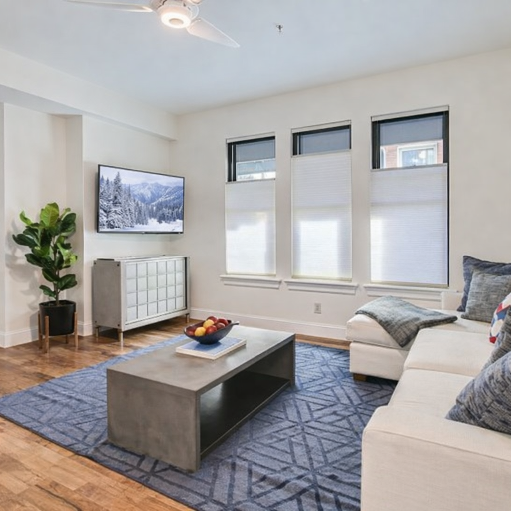 Unwind in your stylish living room featuring a comfortable sectional sofa, smart TV entertainment, and modern furnishings with natural light from oversized windows.