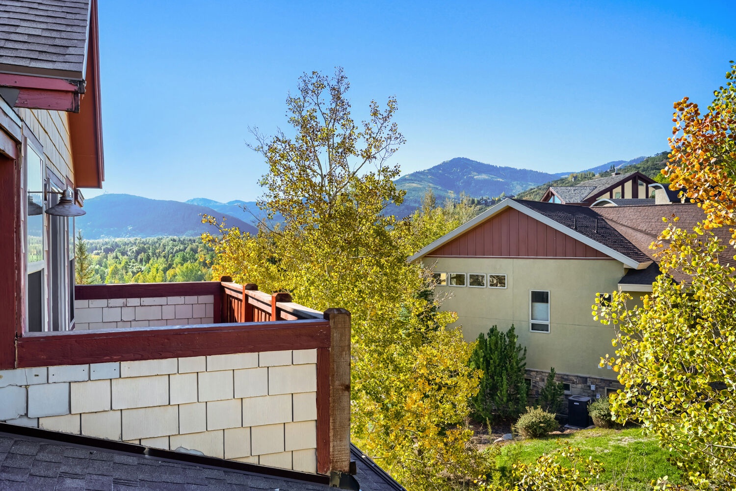 A peaceful mountain neighborhood with rolling hills and lush forests visible in the background. The property is situated among residential homes in a scenic, elevated area with natural surroundings.