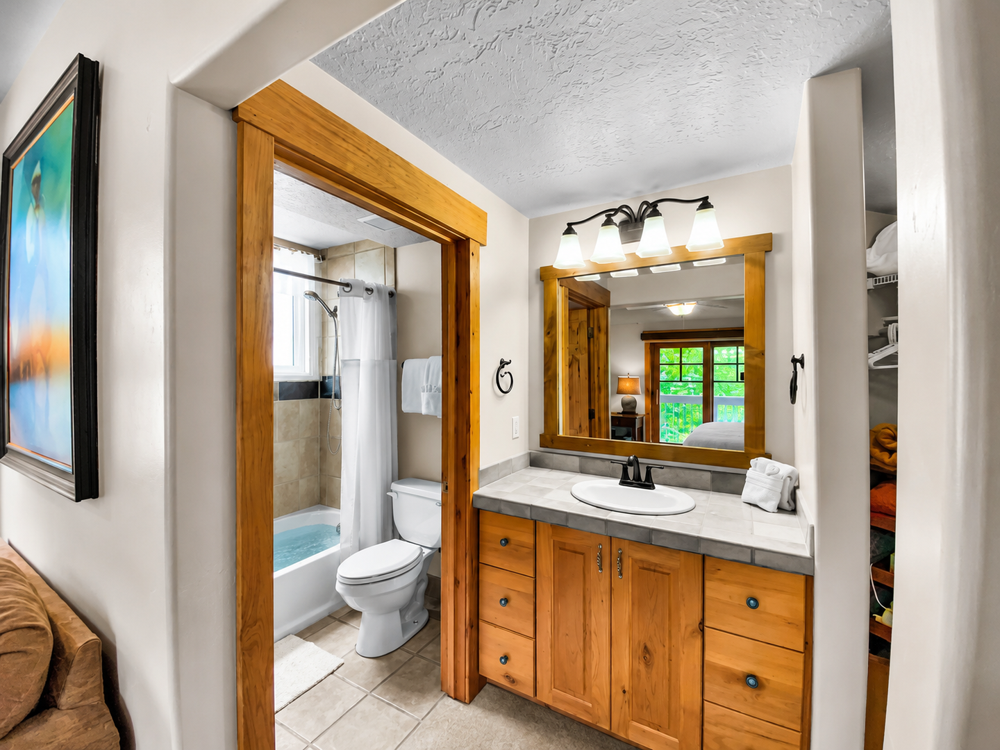 Spacious full bathroom featuring a large double vanity, ample storage in rustic wood cabinets, and a walk-in shower/tub combo with tiled walls. A clean and functional space for your stay.