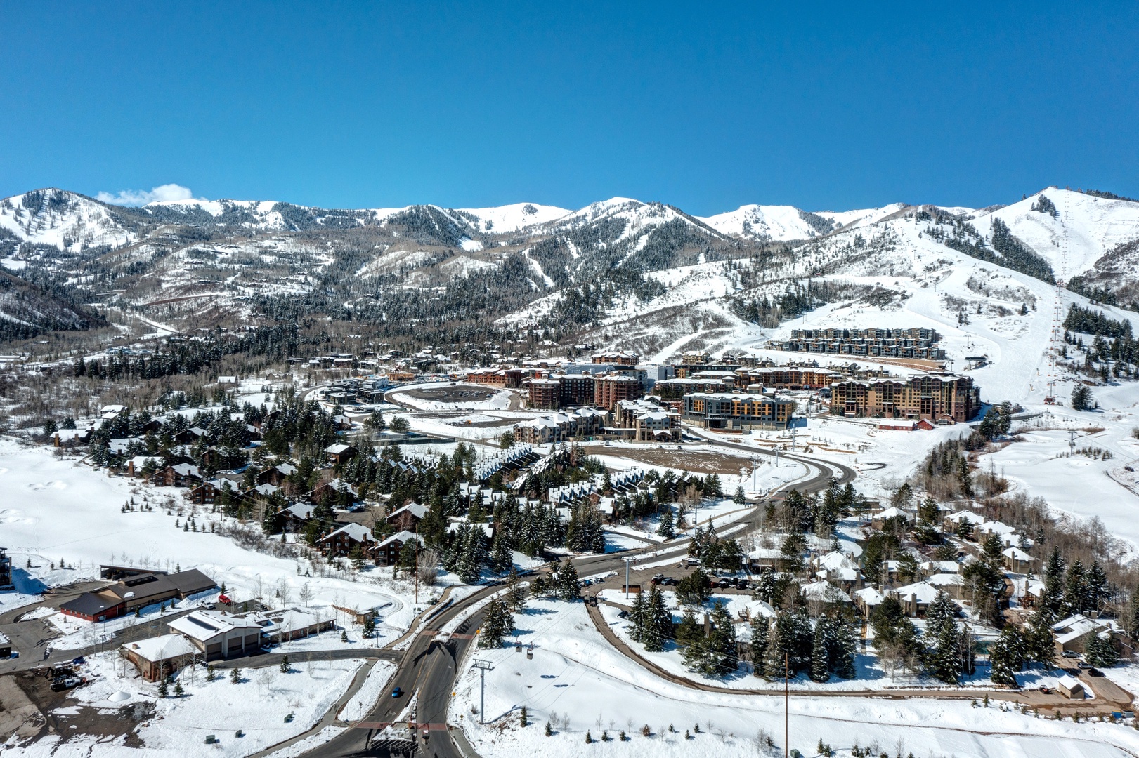 Stunning aerial view of a snow-covered mountain resort town nestled in pristine winter landscape with ski slopes and alpine peaks.