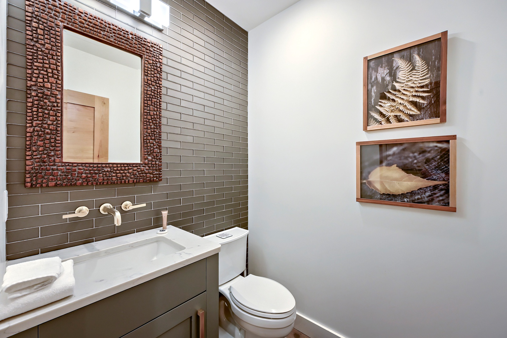 Refresh in your private bathroom featuring natural light, sleek gray subway tile, copper-accented mirror, and nature-inspired artwork creating your serene retreat.