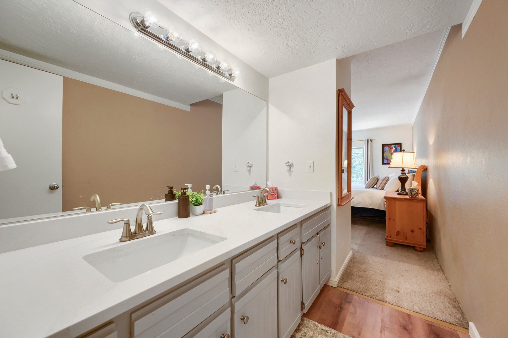 Your private bathroom features dual sinks with a clean, bright vanity and soft lighting—perfect for getting ready in the morning. The bedroom is just steps away, creating a comfortable flow between spaces.